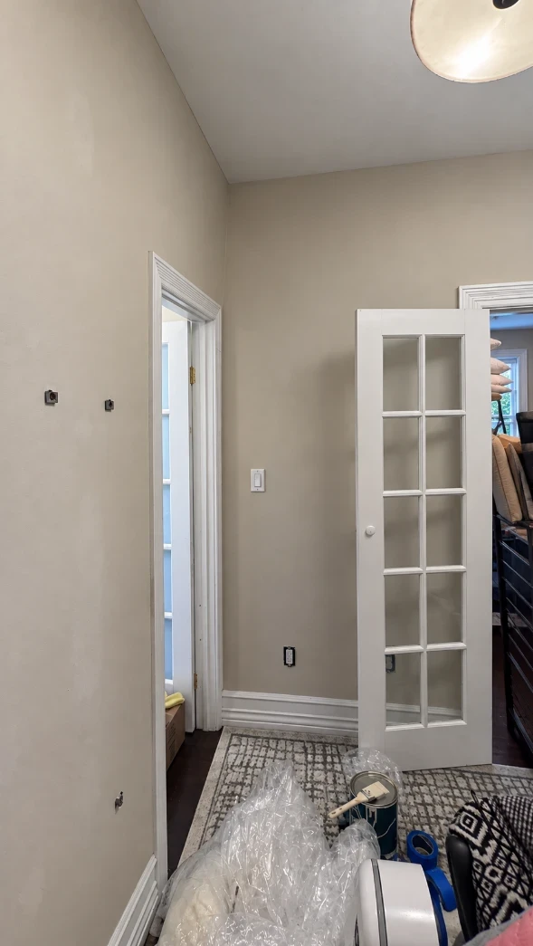 Apartment bedroom with smooth warm taupe walls, a white ceiling, and crisp white French doors, door casings and baseboards
