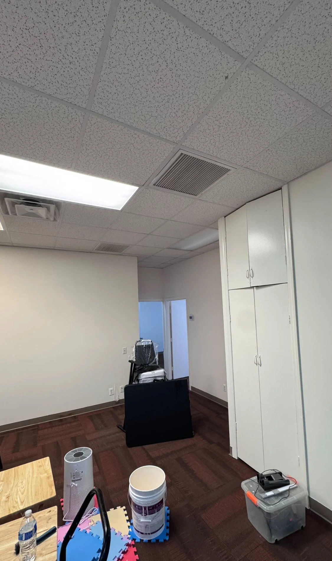 Commercial office room with clean white walls, a white built-in cabinet and a doorway to the next room
